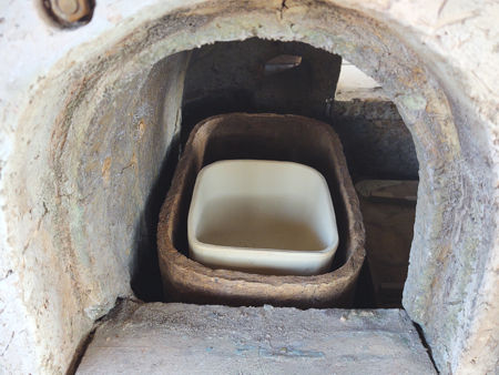 The pot sitting on a layer of sand in the nest