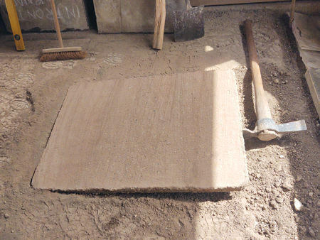 Lifting one of the concrete slabs originally laid as a firm surface for the stools